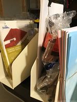 Photo of white plastic upright holders containing envelopes, papers, and office supplies