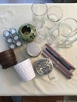 Top-down view of vases, candlesticks, pots, candles and pewter catch all on white surface