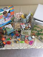 Full view of toddler play items displayed including Aqua Playmat box, craft table, puzzles, toys, and storage box placed on surface.