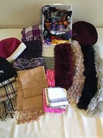 Wide view showcasing scarves of various materials and textures including wool, cotton, silk, polyester, and fuzzy types, along with three hats.