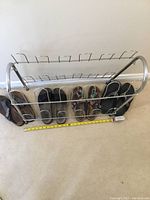 Metal shoe rack holding multiple pairs of sandals, measuring tape showing approximate dimensions