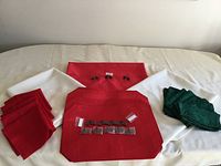 Full view of red placemats, red and white cloth napkins, and green cloth napkins arranged on table with bicycle seating designation items in center.