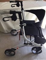 Side view of Excursion X20 folding walker showing frame, wheels, and cloth seat and backrest.