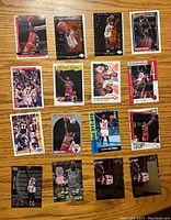 Front side of 16 Michael Jordan basketball cards arranged on wood surface showing player images and design variations.