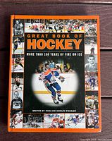 Front cover of the hardcover book 'Great Book of Hockey' showing a central image of a hockey player in Edmonton Oilers uniform and multiple small historic hockey photos in a border design.