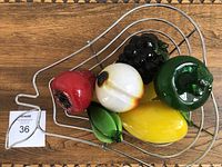 Top view of the metal basket filled with colorful Murano glass fruit pieces including a red strawberry, white peach, green apple, yellow mango, black grape cluster, green starfruit, and a green banana.