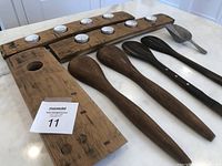 Photo of all collection items laid out on a table: two wooden tea light holders with 8 tea lights total, four wooden salad spoons, and one metal scoop, alongside wooden wine bottle holder.