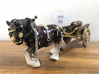 Side view of the ceramic Clydesdale horse figurine hooked to the wooden wagon with barrels, showing the detailed harness and chains.