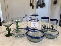 Full view of the glassware set showing margarita glasses, bowls, tumblers, and candle holders arranged on a table.