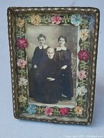 Full view of antique embroidered photo frame with floral needlework and black and white portrait
