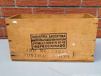 Photo of one side of wooden crate showing black stamped marking 'Industria Argentina Ministerio de Agricultura y Ganaderia Establecimiento No 15 Inspeccionado' and faded stencil text.