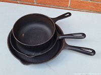 Stack of three cast iron pans showing size variations and handles