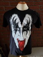 Front view of black medium T-shirt with pixelated Gene Simmons face and red tongue graphic.