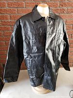 Frontal view of black leather men's jacket on mannequin, showing button closure and collar.