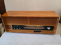 Full front view of the vintage German shortwave radio showing the wood cabinet, slatted speakers, and tuning dial.