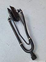 Photo showing black Y-shaped testing device with two headphone-like earpieces and tubing, resting on a light surface