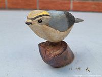 View of front-left side of carved and painted wood bird figure showing detailed paint and mounted wooden base.