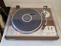 Front view with dust cover closed showing platter, tonearm and control panel.
