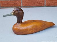 Photo of side profile showing smooth natural wood body and painted head detail of carved duck decoy