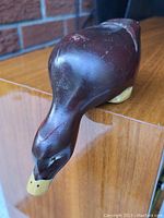 Top-front angled view of the carved wood duck figure showing the head, beak, and body detailing including the painted eyes and feather accents.