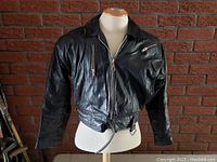 Front straight view of vintage ladies black leather bomber biker jacket on dress form, showing collar, zipper closure, and belt strap at bottom.