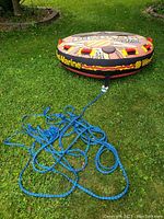 Inflatable tube with attached blue tow rope laid out on grass, showing tube shape and rope length.
