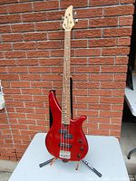 Front full view of red bass guitar on table