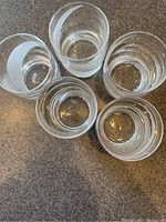 Top-down view of 5 clear Lenox glasses with frosted swirl patterns, arranged in a circle on grey surface.