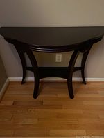 Front view of the Bombay Company console table showing the half-moon shape and curved legs against a wall.