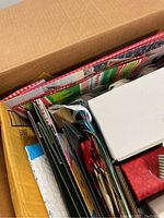 Top view showing assorted gift bags with characters and holiday themed prints along with white gift boxes and colorful smaller boxes inside a larger cardboard box.
