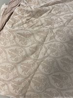 Close-up of damask patterned fabric in a beige tone.