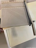 Photo of paper cutter showing grid measurement surface and wooden handle
