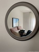 Front view of the round silver mirror reflecting a bedroom interior