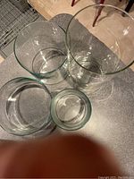 Top and angled view of four clear glass cylindrical vases on a table showing varying heights and diameters.