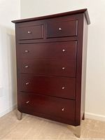 Full view of the tall wooden dresser with five drawers and metal legs.