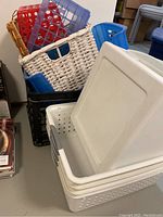 Overview of various plastic and wicker storage bins stacked together showing different shapes, colors, and materials.