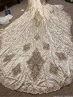 Full view of the long ivory satin piano train with multiple large beaded and embroidered diamond-shaped appliques.