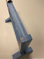 Side view of blue painted wooden marble game with scratches and wear.