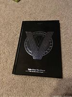 Front cover of the WayV Take Over The Moon album showing the large V emblem and album title on black matte cover.