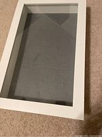 Top view of the white display box showing transparent glass and grey padded interior.