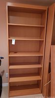 Front view of one laminate display shelf unit with multiple adjustable shelves and light wood finish.