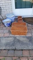 Photo showing four round flower pots (two large blue and white ceramic, two small terracotta) in front of a white door and two rectangular terracotta pots in front.