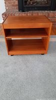 Front view showing top surface and two shelves of the mid-century modern wooden cart.