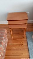 Three nesting tables stacked in corner showing full set