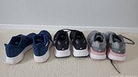 Three pairs of ladies' running shoes viewed from the back, showing two Fila pairs and one Reebok pair.