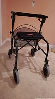 Front view of Nexus folding walker showing padded seat, hand grips, and front wheels.