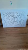 Front view of white textured canvas wall art showing geometric raised pattern in radial design.