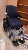 Full view of the portable Litestream wheelchair showing blue cushioned seat and backrest, armrests, and front and rear wheels.