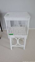 Two white wicker nesting tables stacked together showing size difference and detail of weaving.