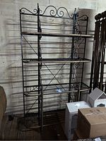 Full view of large metal baker's rack showing multiple shelves and scrollwork design.
